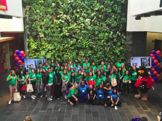 Large group of students in front of plant wall