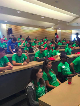 Group of students in green orientation shirts in lecture hall