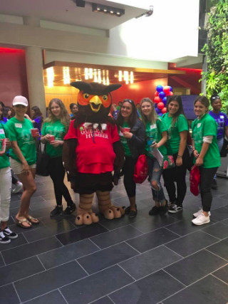 Six students in green orientation shirts with Swoop mascot