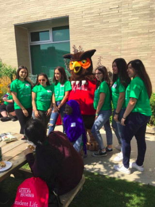 Seven students posing outside with Swoop mascot