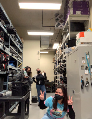 Three students posing in media equipment storage room