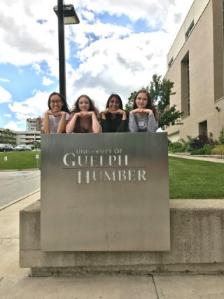 Four students posing above Guelph-Humber building sign outside