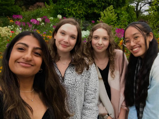 Four students posing in front of flowers