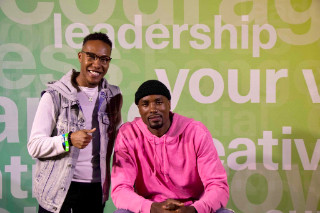 Two men posing in front of wall with the word 'leadership' visible