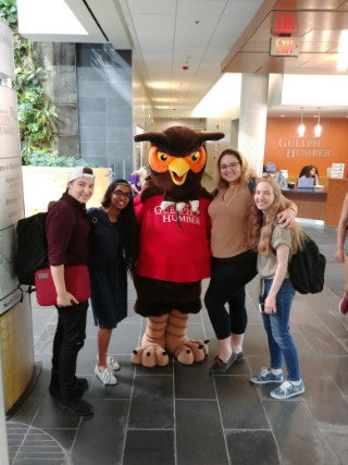 Four students posing with Swoop mascot