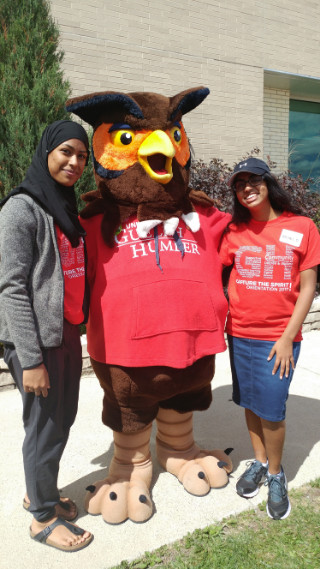 Two students in red orientation shirts posing with Swoop mascot