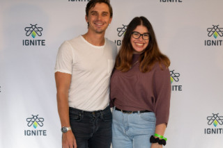 A man and woman posing in front of an 'IGNITE' backdrop
