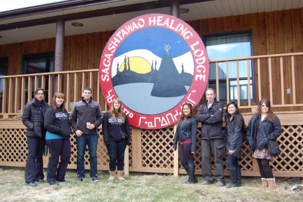 Eight people posing in front of Sagashtawao Healing Lodge