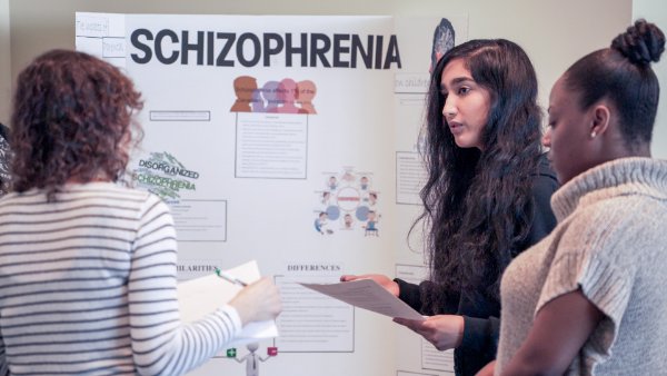 Three people in front of 'Schizophrenia' display board
