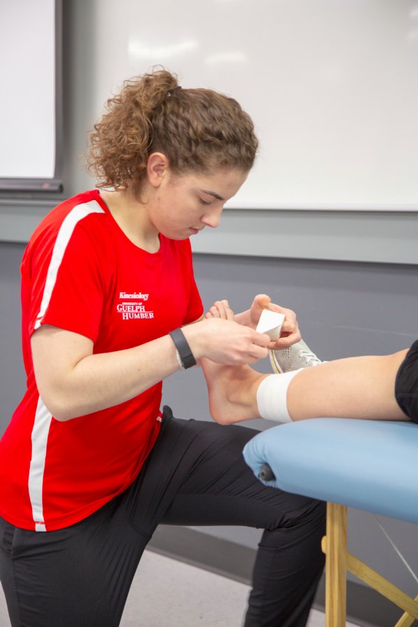 Student wrapping an ankle with support tape