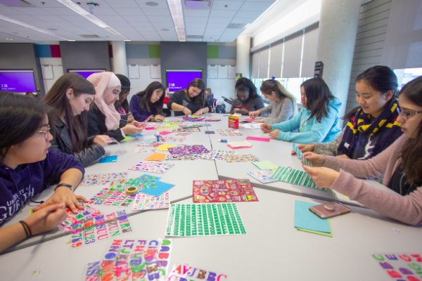 Students seated at a table with craft supplies