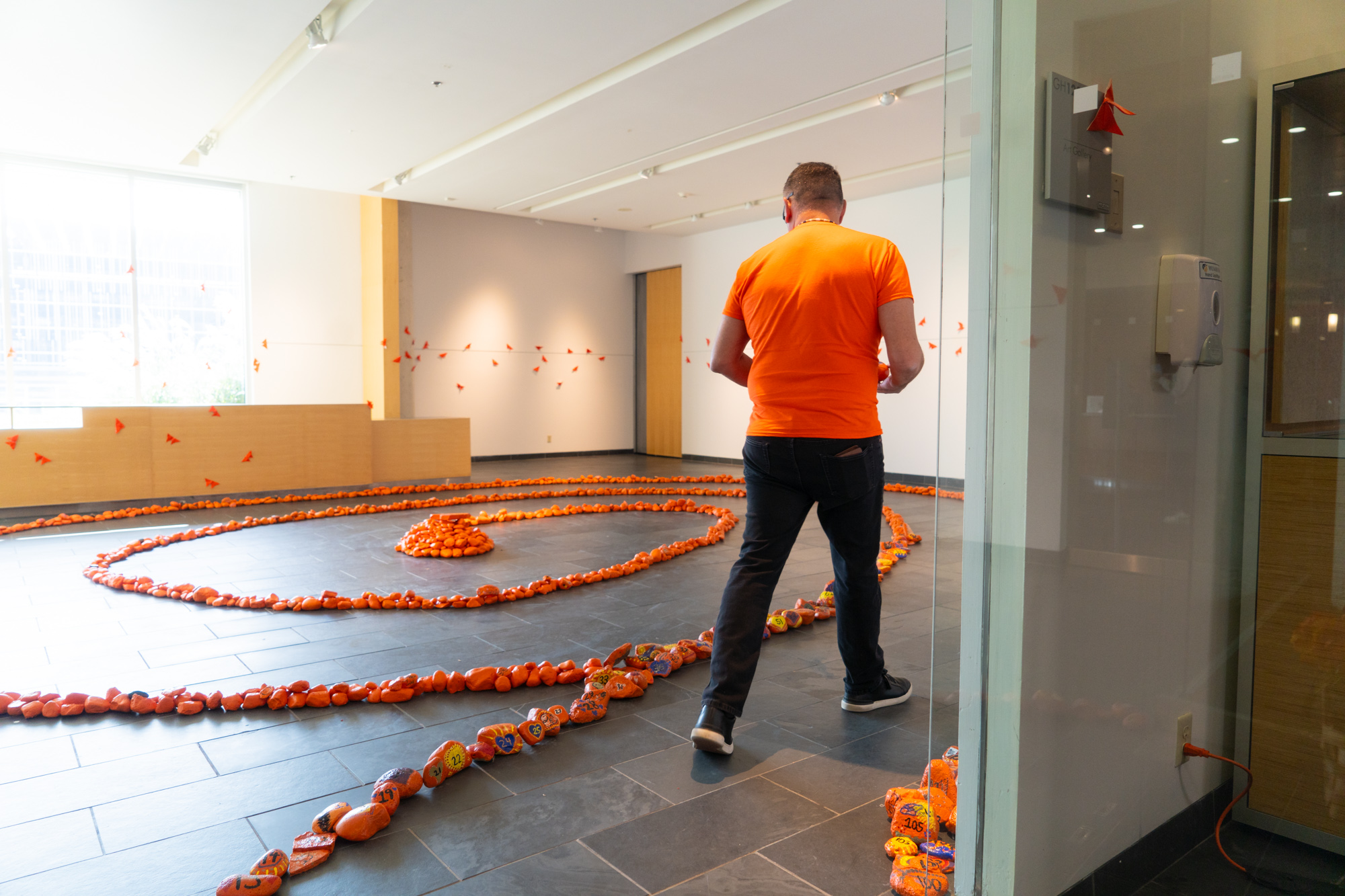 Someone walking through a labyrinth of orange painted rocks 