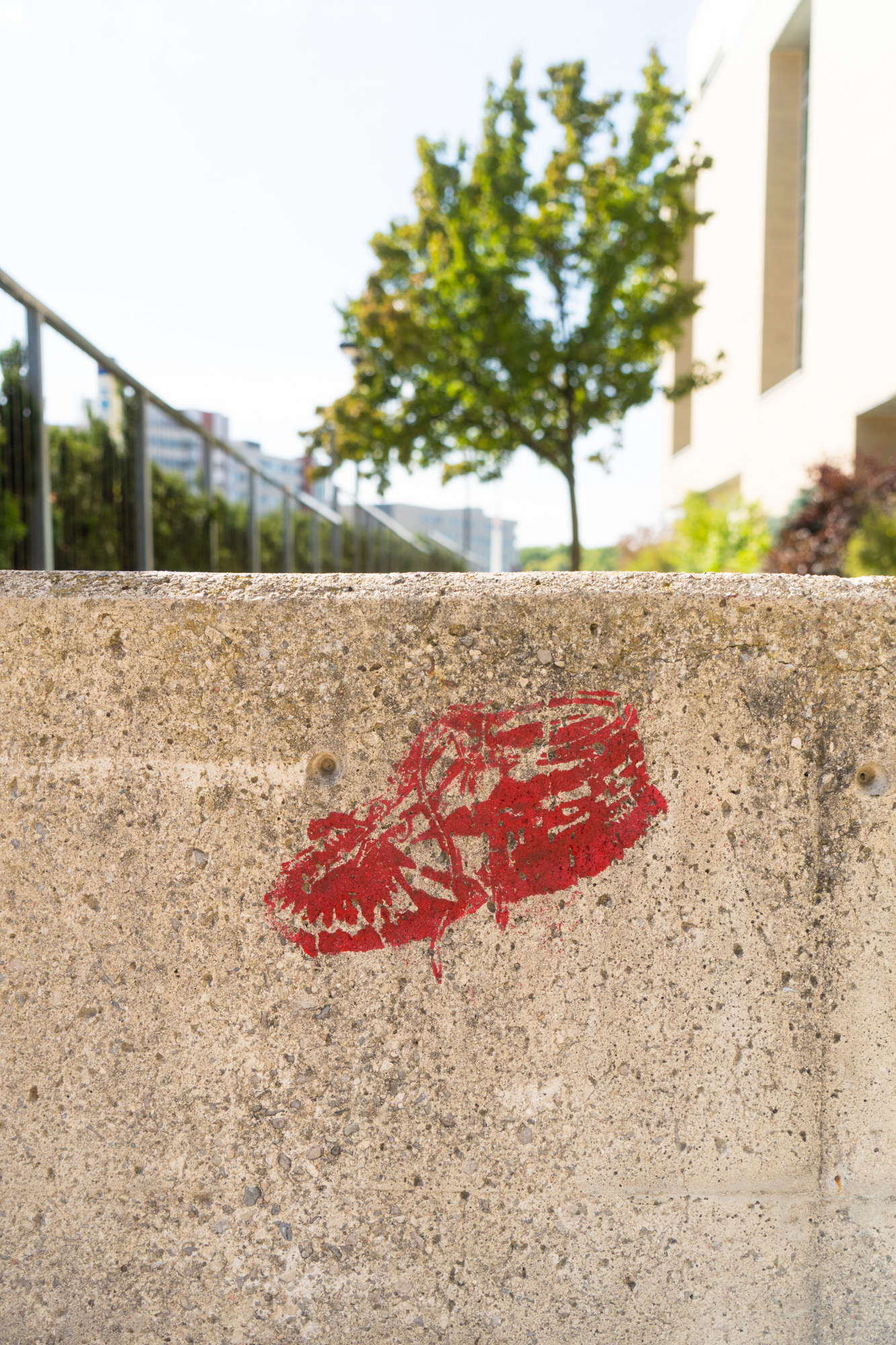 A red painted moccasin stencil is on a wall of concrete