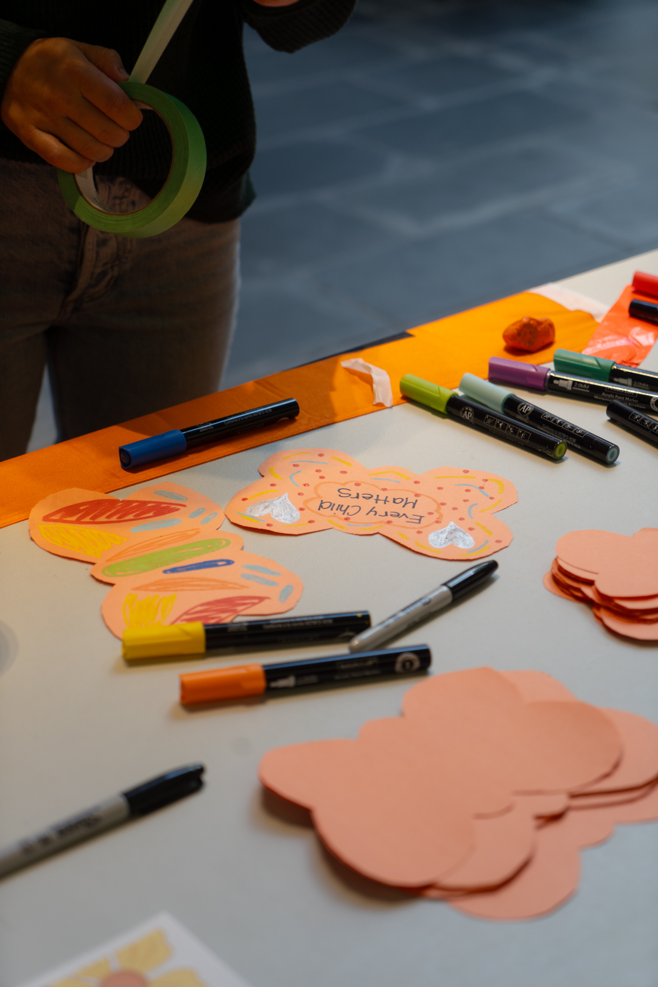 A table with orange butterfly-shaped papers and markers spread across with one paper that writes, 'Every Child Matters'