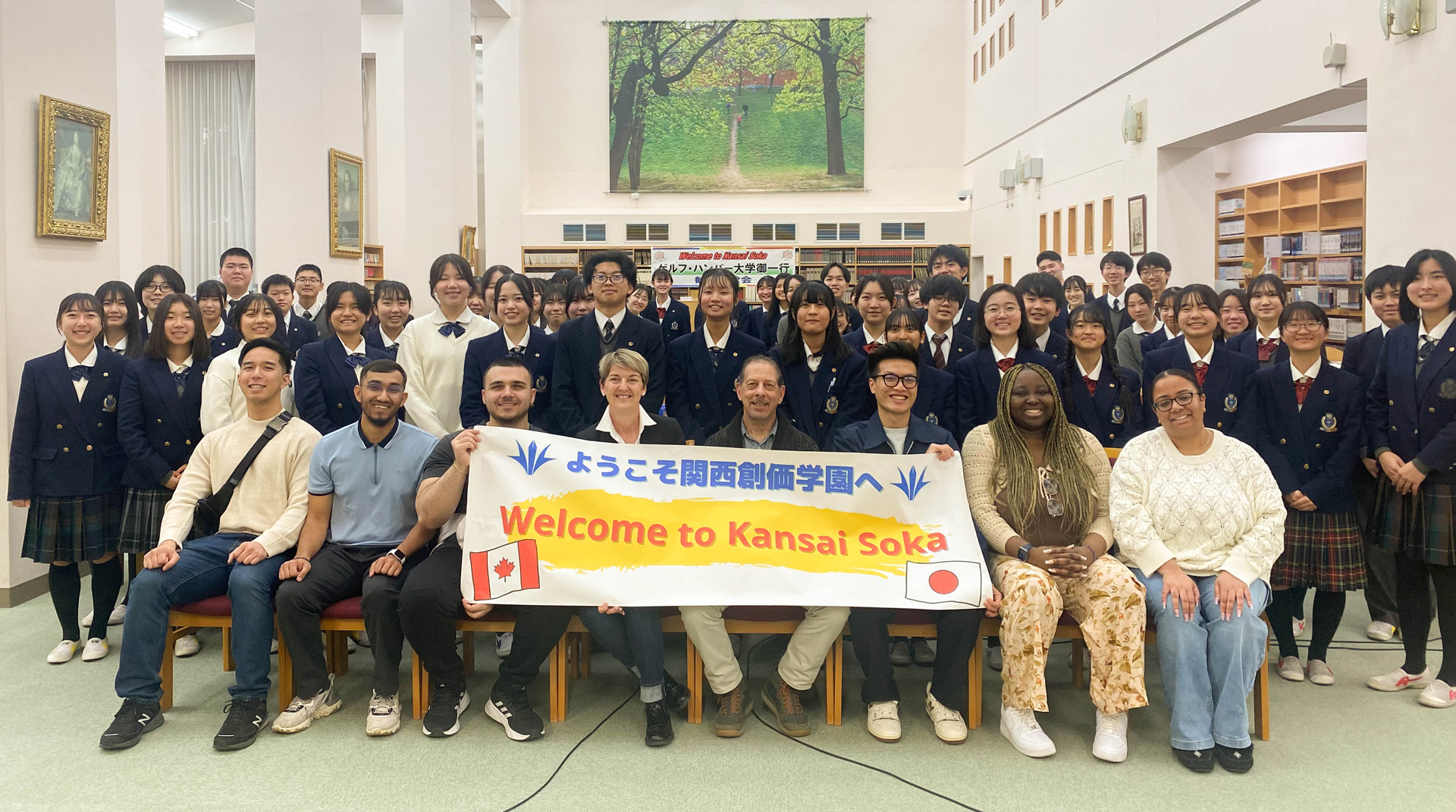 A group photo with a banner that says, "Welcome to Kansai Soka" in Japanese and then English