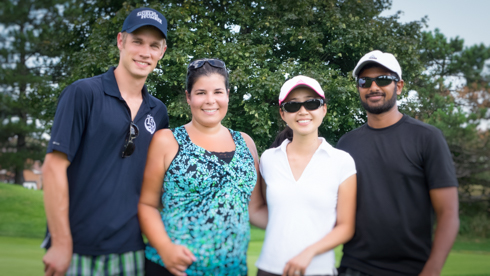 Group photo of 4 UofGH alumni on golf green