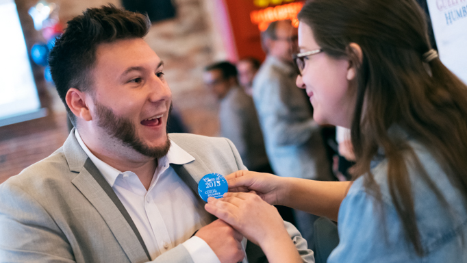 An alumnus has his button pinned to his shirt