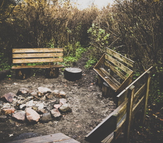Nature classroom consisting of three benches and a fire pit in the woods