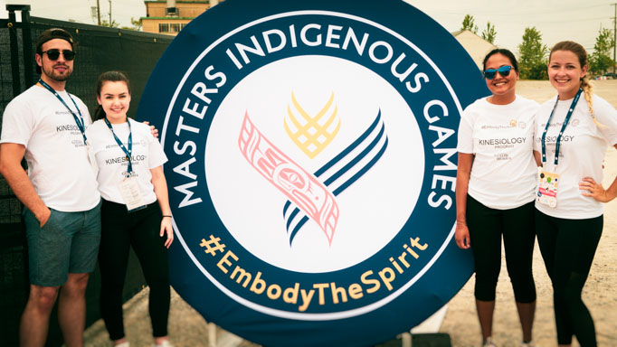 Four UofGH students pose with the Masters Indigenous Games logo