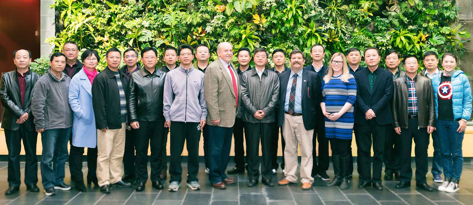 The entire Chinese delegation poses in front of the plant wall