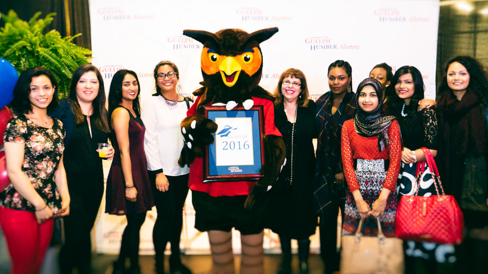 Swoop holding an award with students.