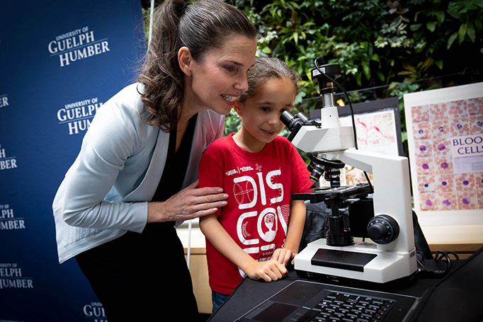 Minister Duncan helps a child look through a microscope