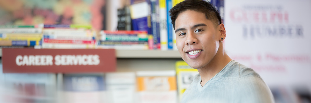 Student standing beside a sign that says career services.