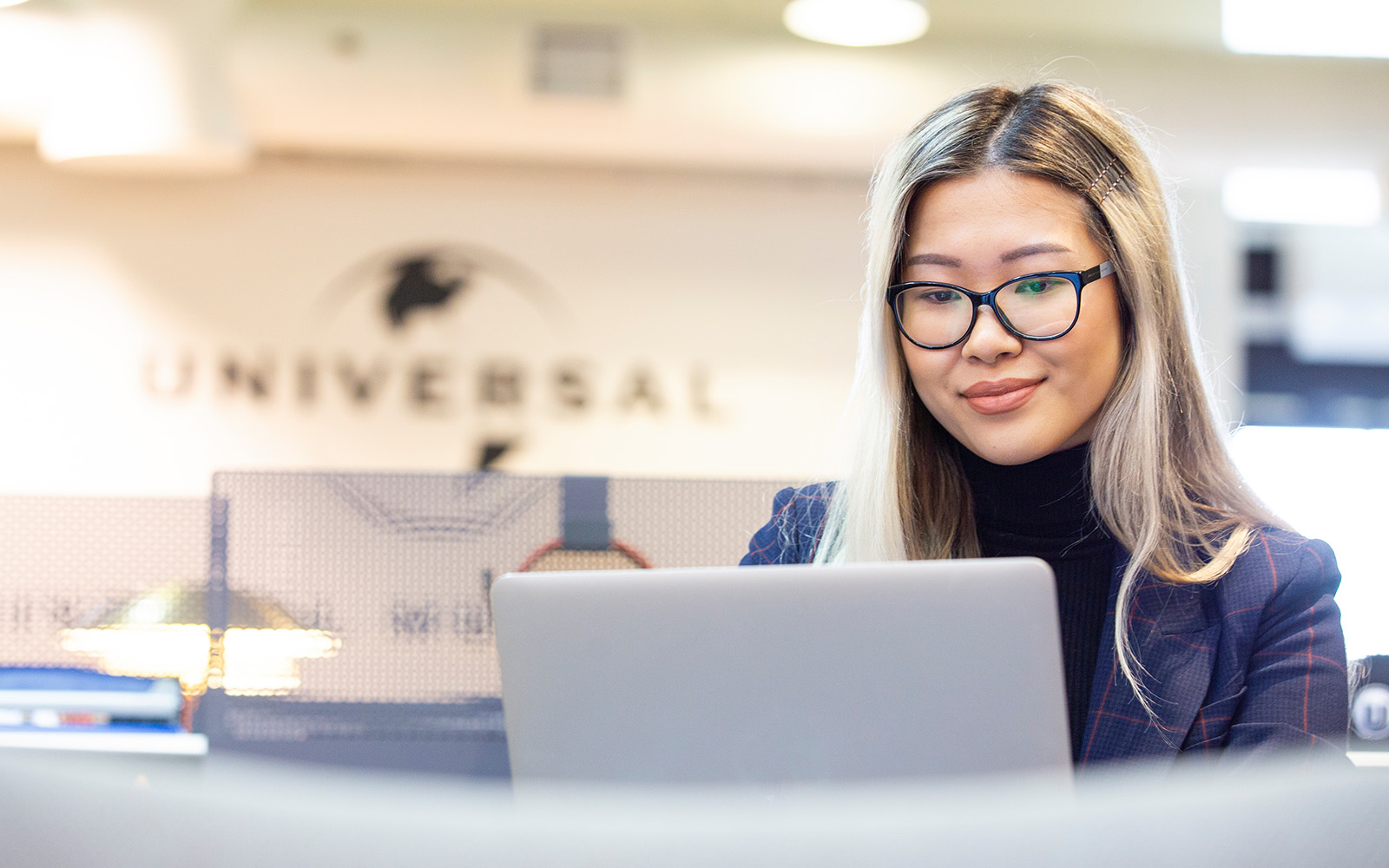 student looking at laptop in universal office