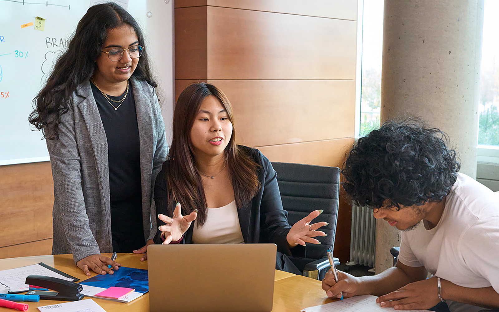 three students around a laptop