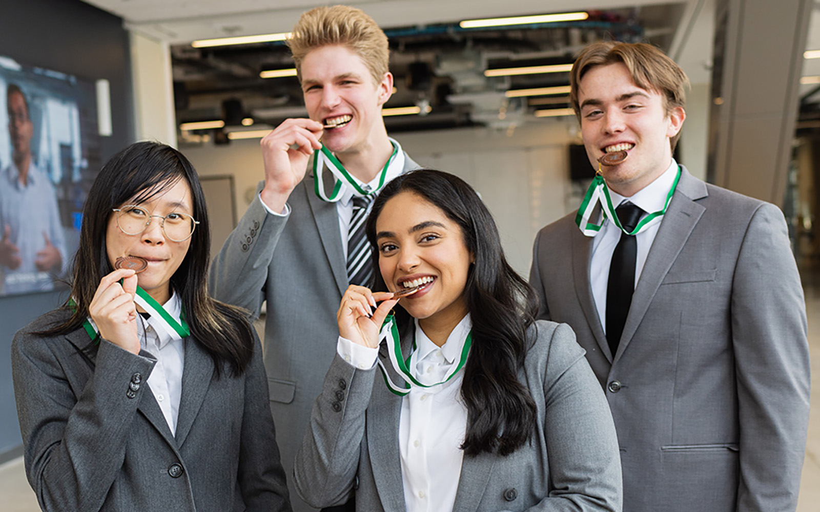 four students biting medals