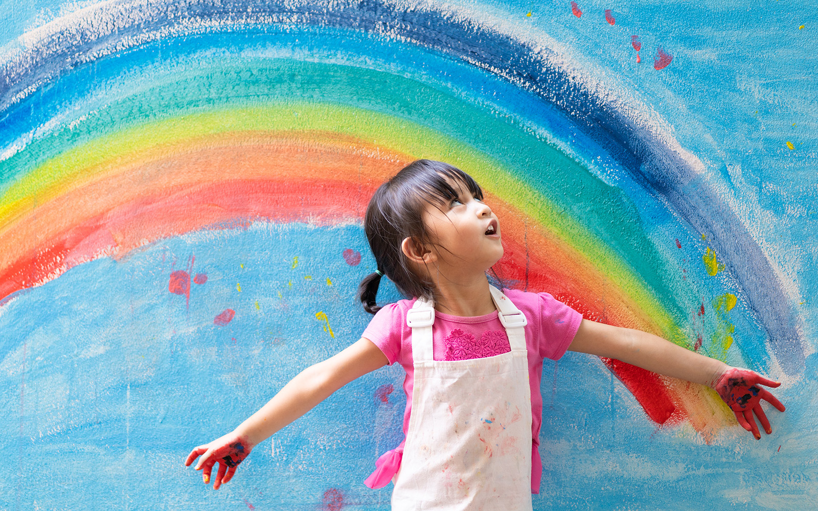 Child in front of rainbow painting