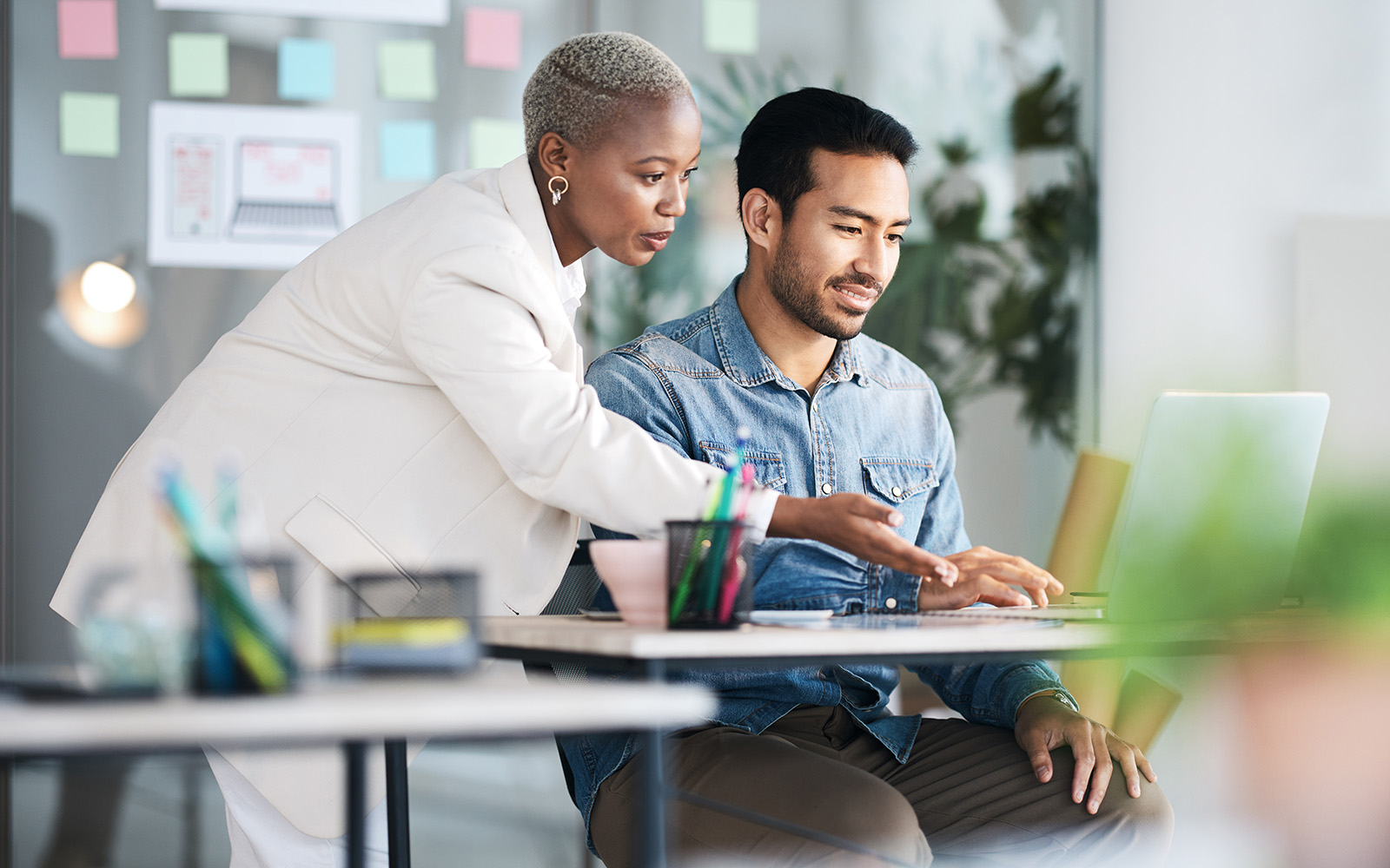 boss helping employee at laptop