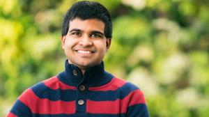 Student smiling infront of plant wall