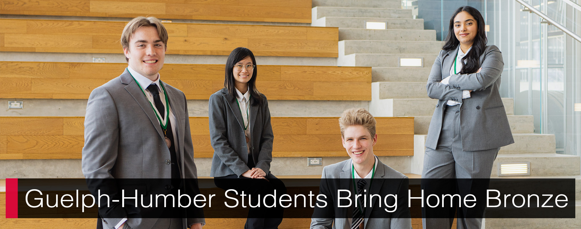 Four students posed amongst a wood and concrete staircase, looking at the camera. Text writes, 