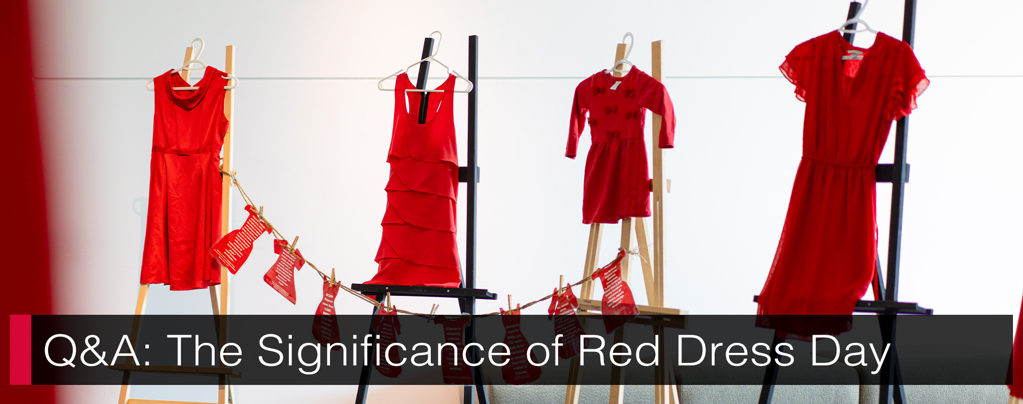 Four red dresses hung on clothes hangers displayed on easels with text, 