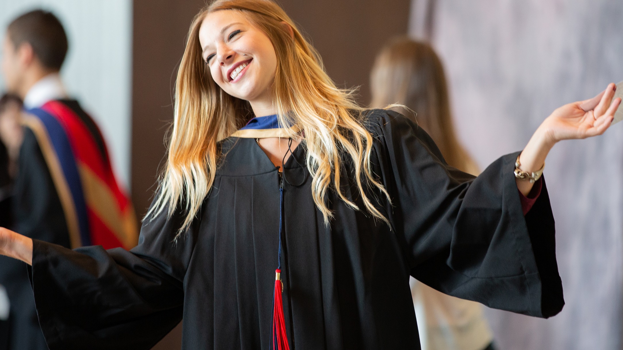 Graduate wearing convocation gown with arms outstreached