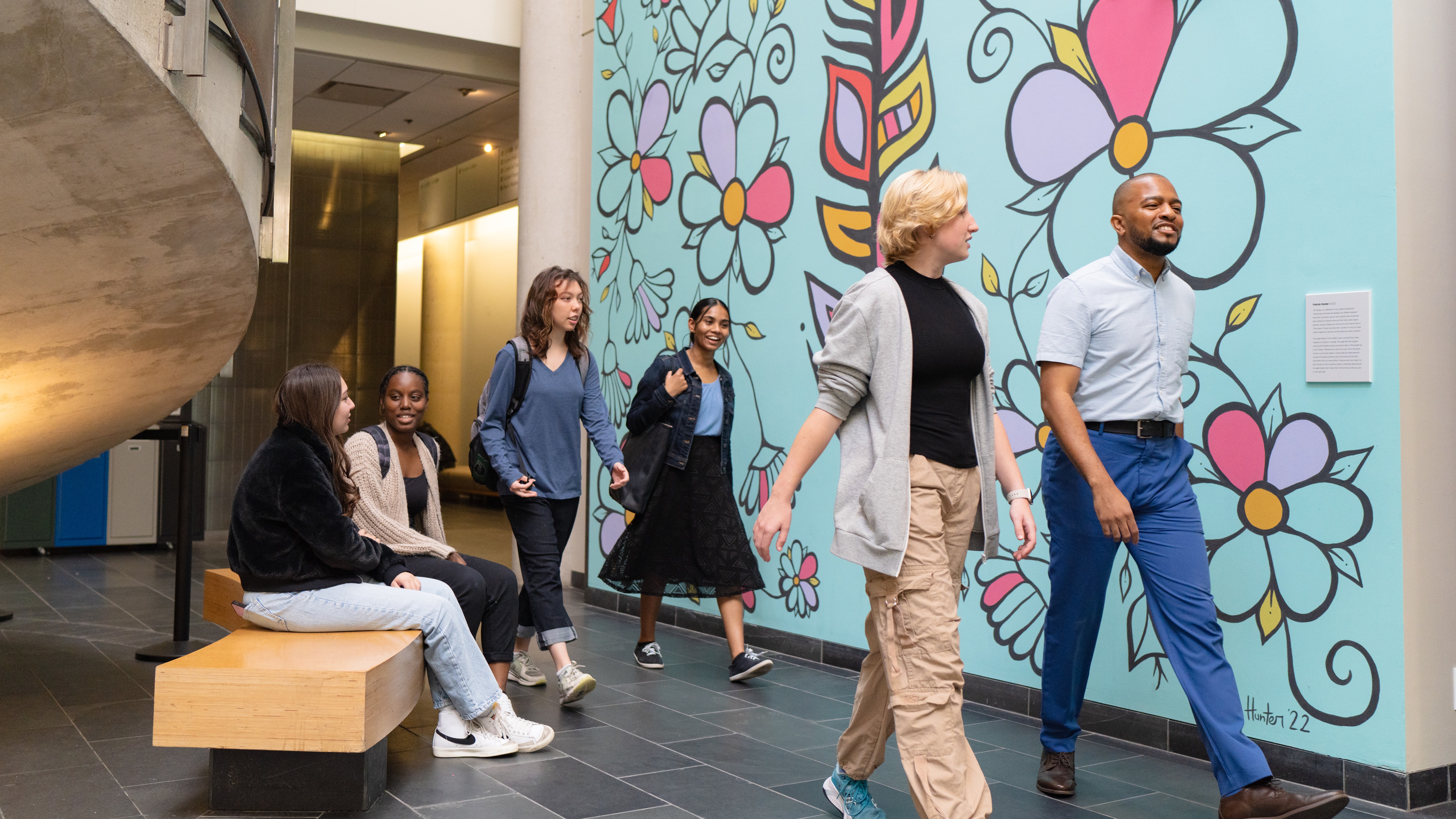 Students walking past the Indigenous art mural in the atrium