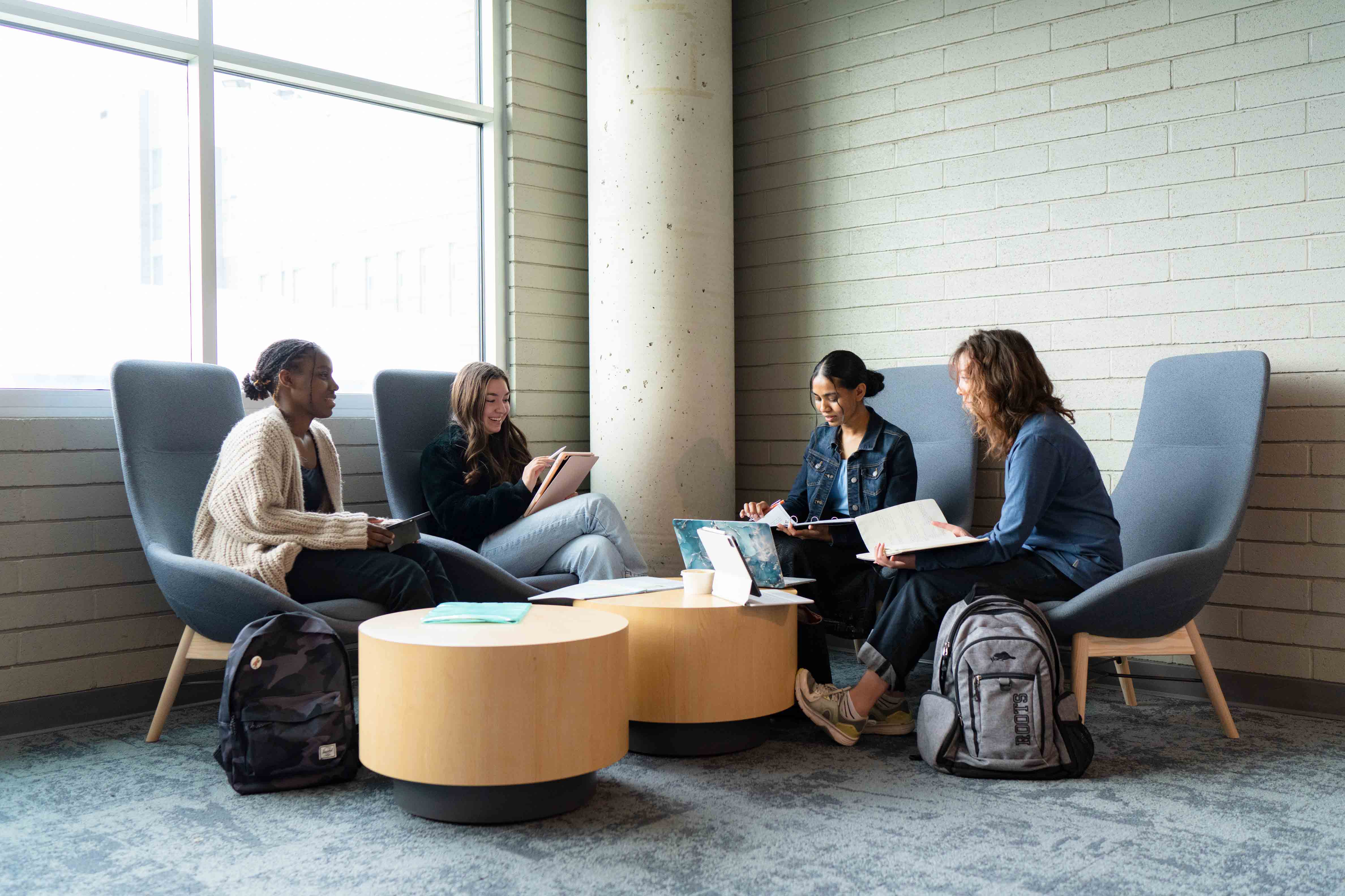 Four students sitting around a round coffee table with notes out on their laps