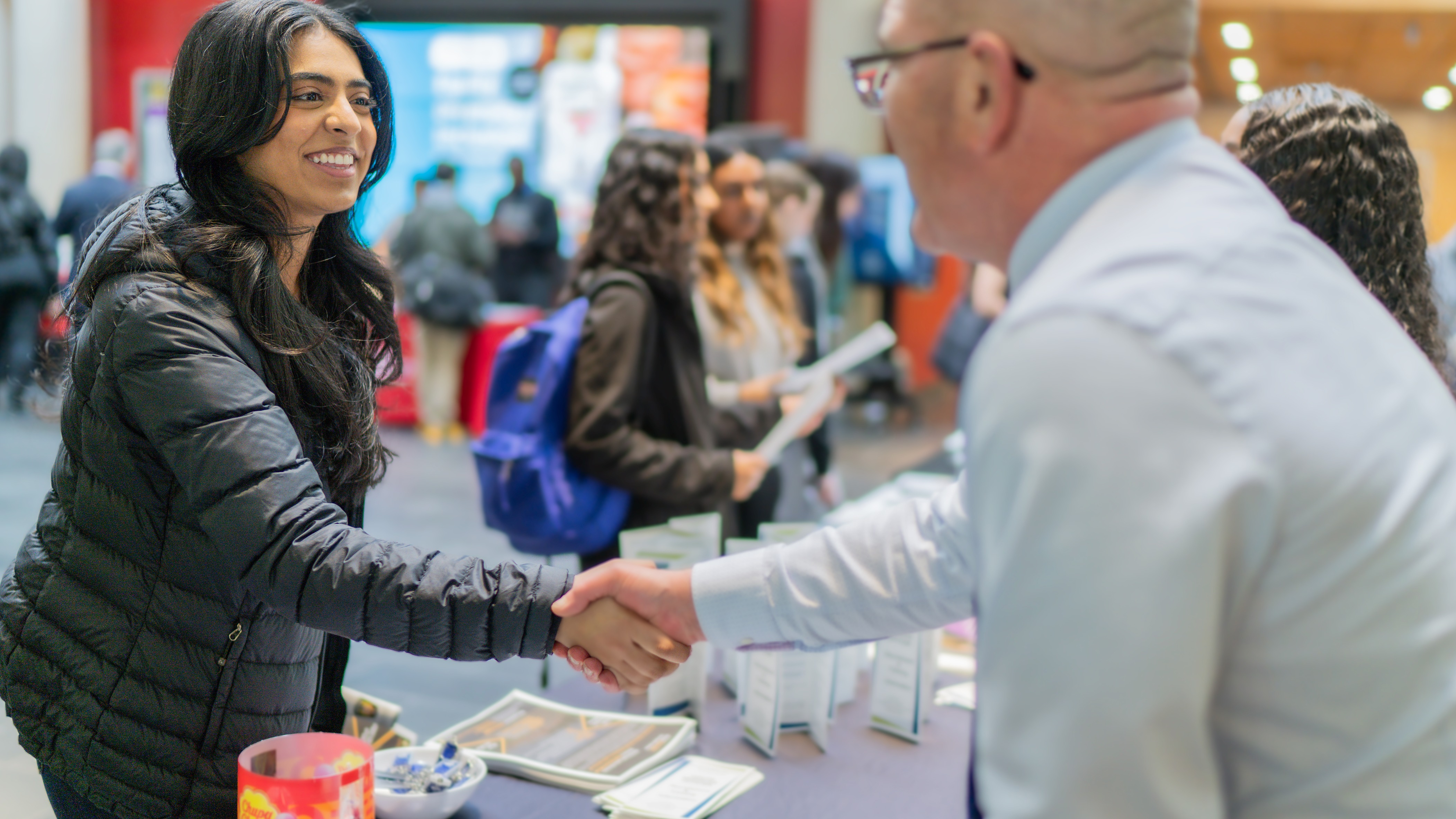 Student and employer partner shaking hands at a career fair