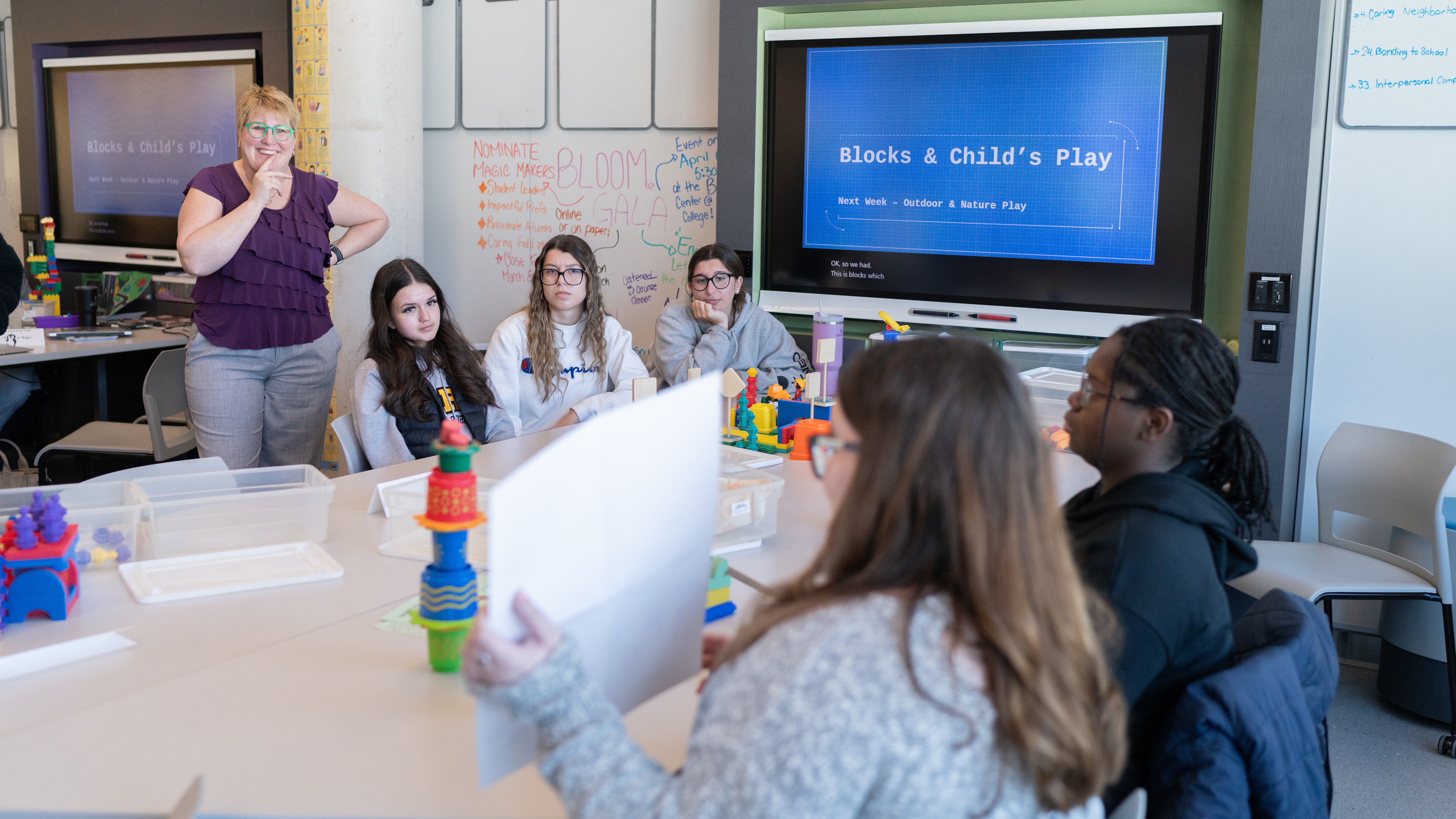 Instructor with a group of students at a desk with a screen