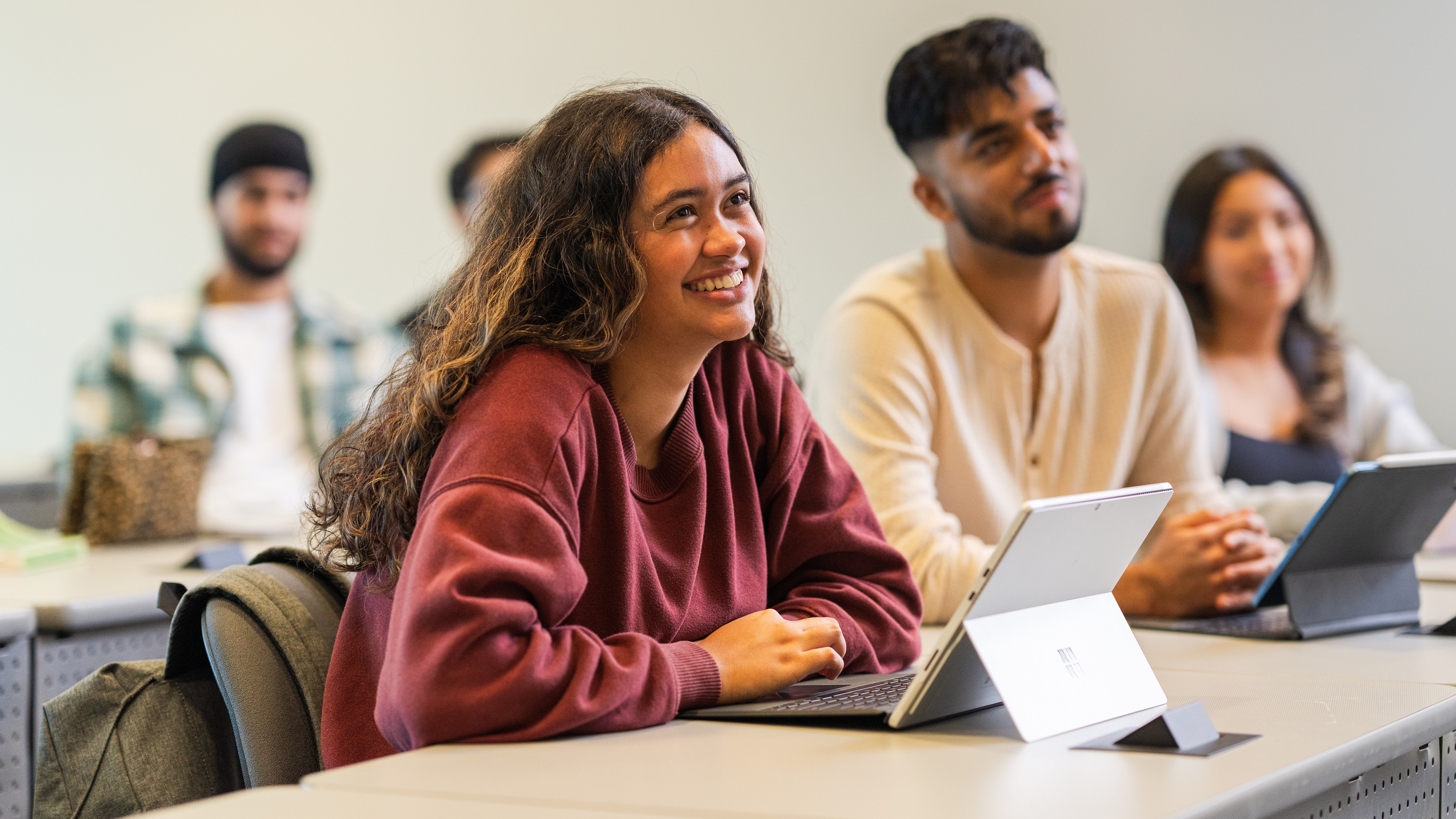 Students sitting at desk with laptop computer smiling