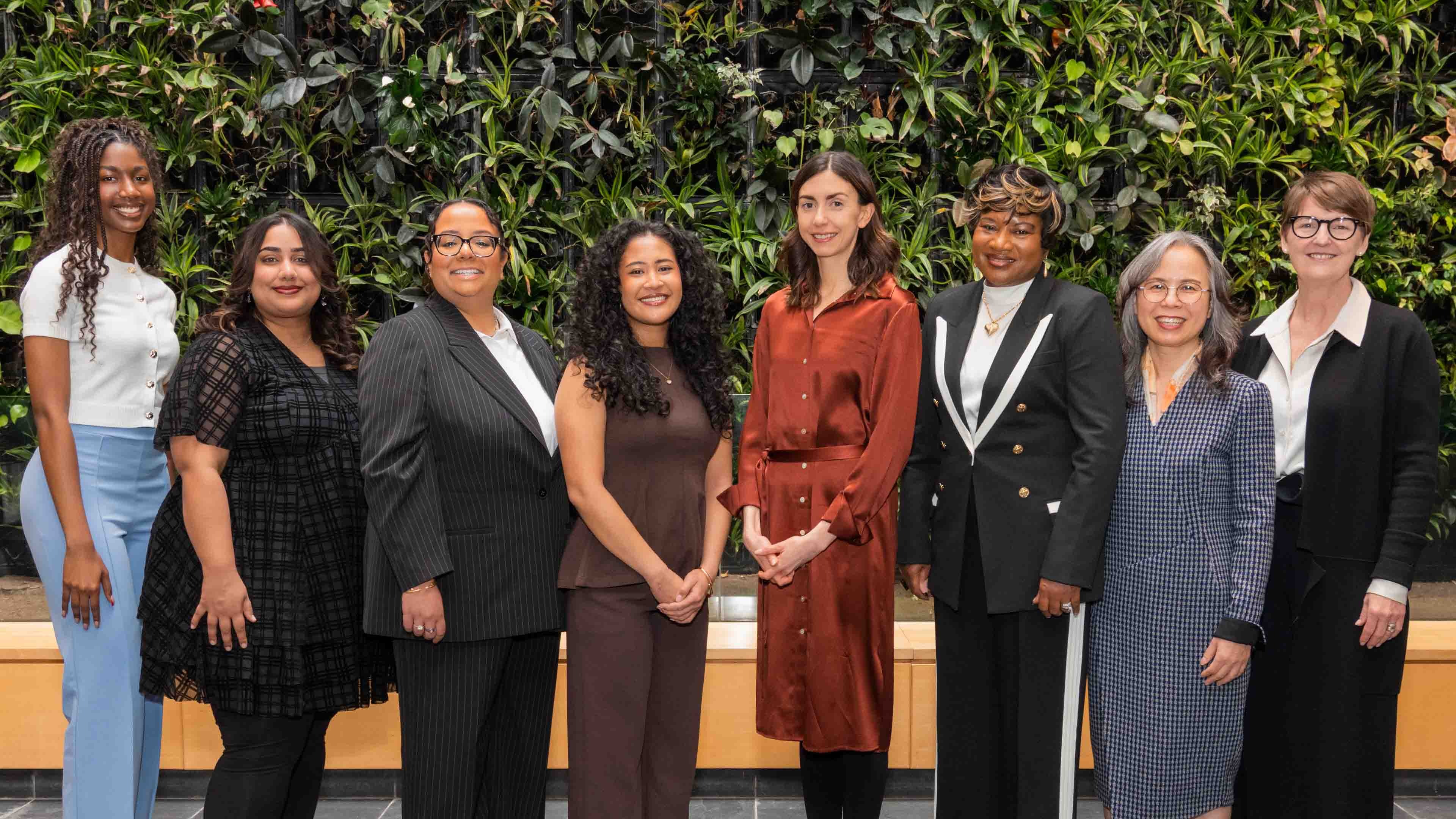 Group of eight women in front of plant wall
