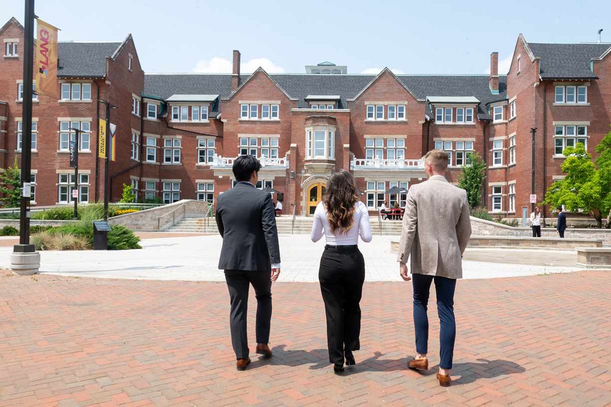 Three students walking toward building