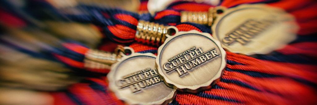 Gold circular graduation medals with red and blue ribbons reading “University of Guelph-Humber.”
