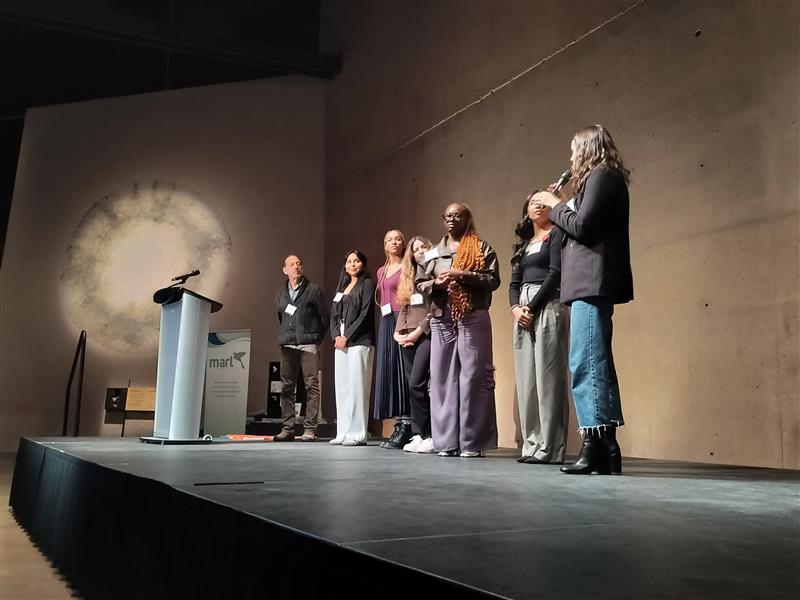 Group of students on stage near a podium giving a presentation