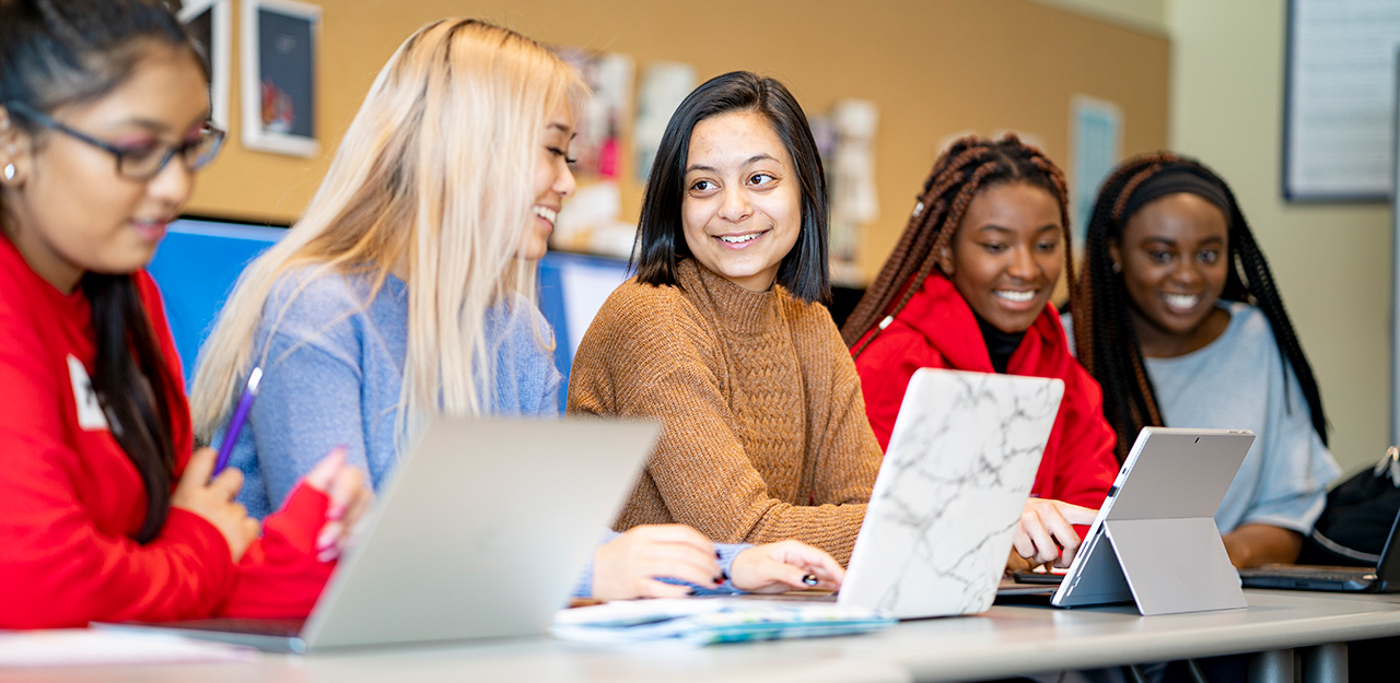 Five students with laptops in classroom