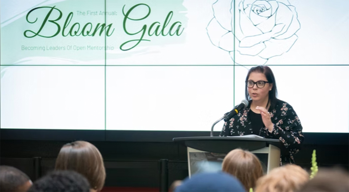 Bloom Gala Female speaking at podium in front of screen