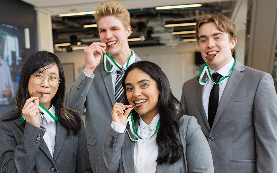 Case competition winners Four students biting medals