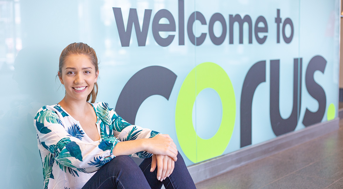 Corus placement female student in front of corus sign