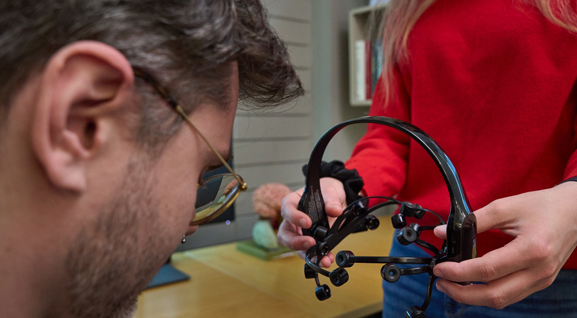 EEG machine woman in red sweater putting headset on man